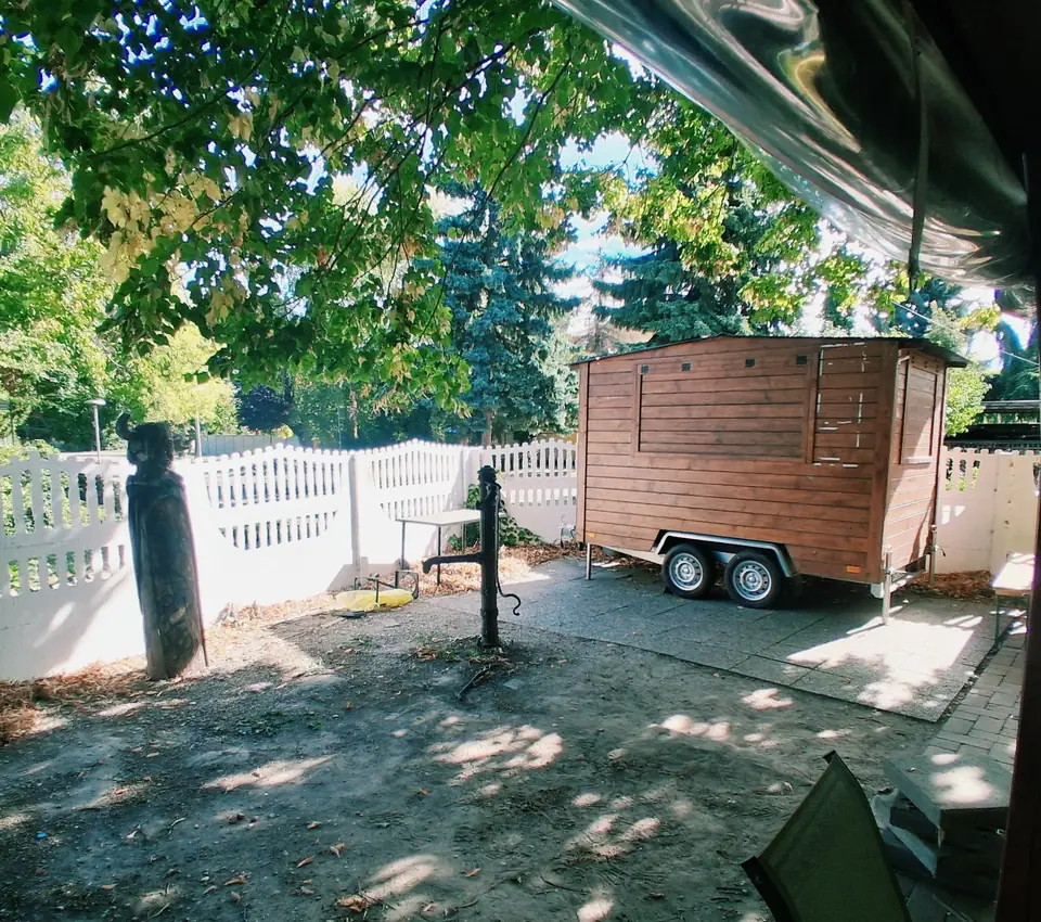 Drevený food truck v záhrade pri bielom plote